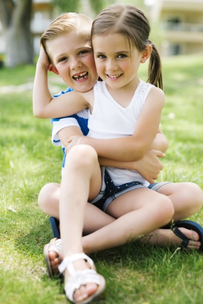 Sister and brother (4-5, 6-7) embracing in park