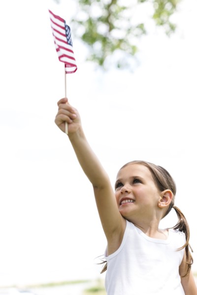 Smiling girl (4-5) holding american flag