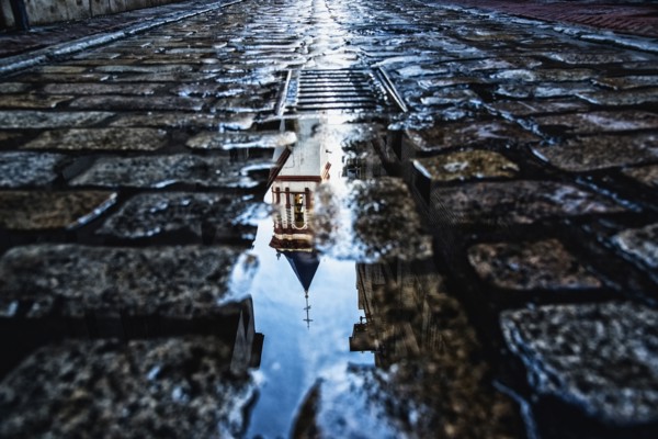 Spain, Andalusia, Seville, La Macarena, Church reflecting on wet cobblestone street