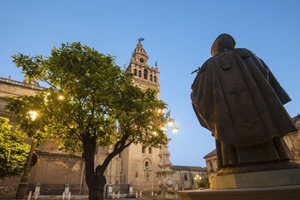 Spain, Seville, Plaza Virgin De Los Reyes, Statue and Giralda Tower at dusk