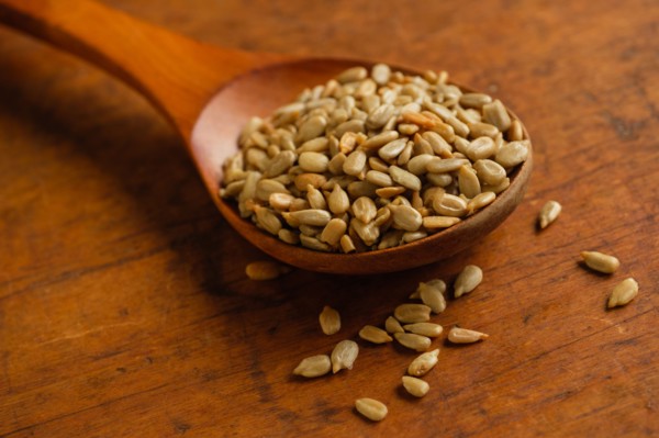 Wooden spoon full of sunflower seeds on table
