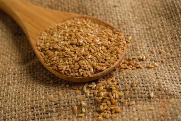 Wooden spoon full of flax seeds on burlap