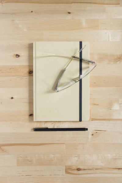 Diary, eyeglasses and pen on wooden desk