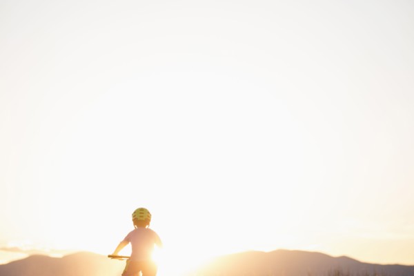 Rear view of boy (8-9) cycling at sunset