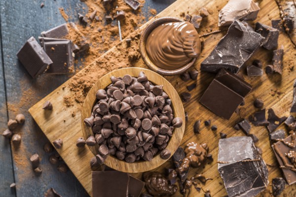Various chocolate pieces and melted chocolate on cutting board