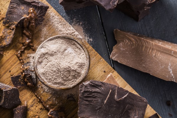 Various chocolate pieces and chocolate powder on cutting board