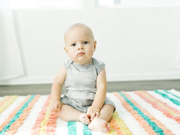 Portrait of baby boy (6-11 months) sitting on colorful carpet