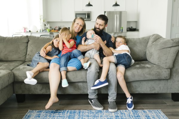 Family with four children (6-11 months, 2-3, 6-7) spending time on sofa
