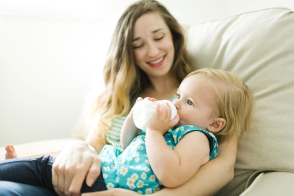Mother feeding baby girl (12-17 months) in living room