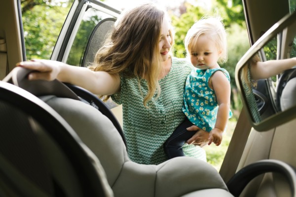 Mother preparing baby girl (12-17 months) for car trip