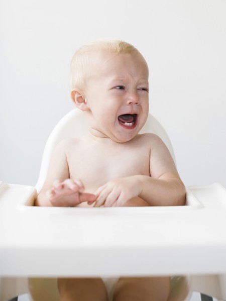Baby boy (12-17 months) sitting in high chair and crying