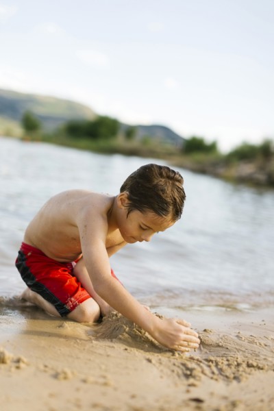 Boy (6-7) playing on beach by lake