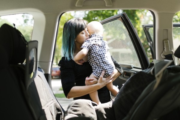 Mother carrying baby boy ( 12-17 months ) into car