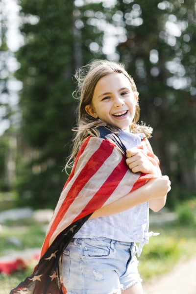 Portrait of girl (8-9) wrapped in us flag in forest