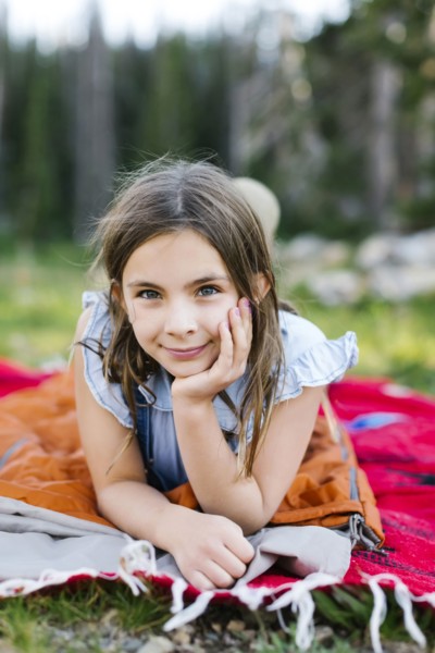 Portrait of girl (8-9) lying on blanket in forest