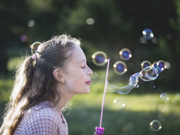 Girl (12-13) blowing bubbles