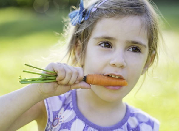Little girl (4-5) eating carrot