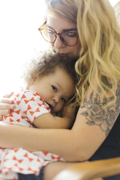 Mother sitting on chair and embracing daughter (12-17 months)