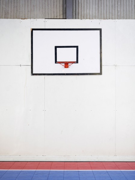 Empty basketball court with basketball hoop hanging on wall