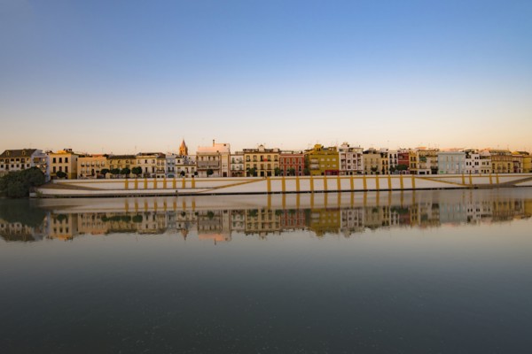 Spain, Seville, Colorful residential building reflecting in Guadalquivir river