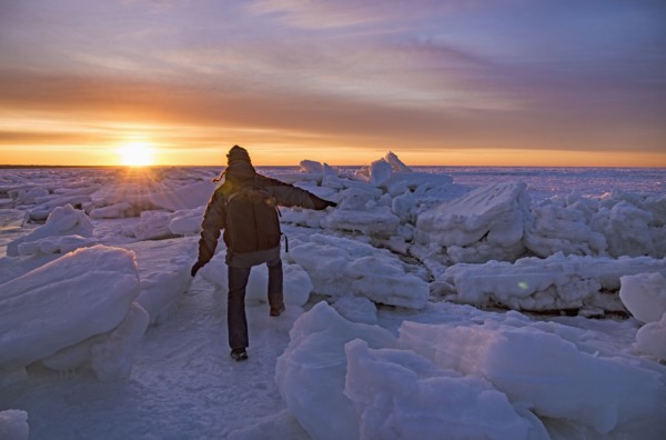 USA, Massachusetts, Cape Cod, Eastham, Man balancing on sea ice at dusk
