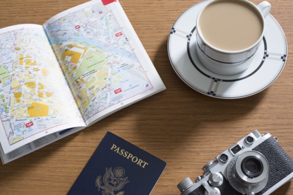 Passport, coffee, old camera and open guidebook