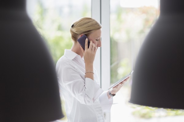 Woman talking on phone and using digital tablet