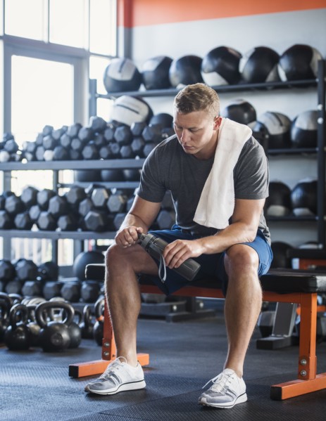 Mid adult man with towel and bottle in gym