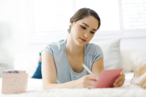 Woman writing in card on bed