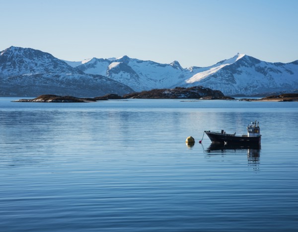 Fishing boat by snow covered mountains in Tromso, Norway
