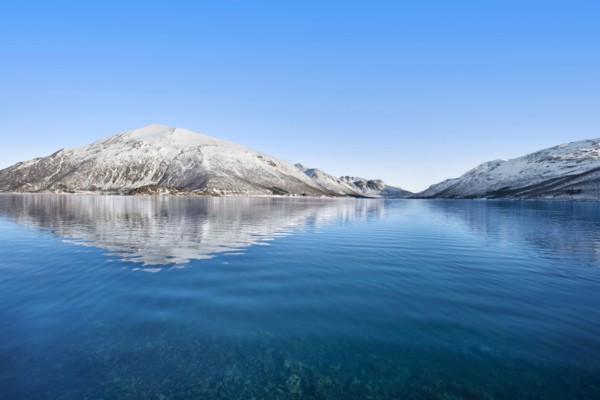 Snow covered hills by sea in Tromso, Norway