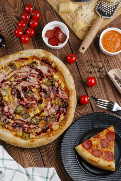 Pizza and ingredients on wooden table