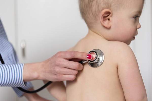 Paediatrician using stethoscope on girl