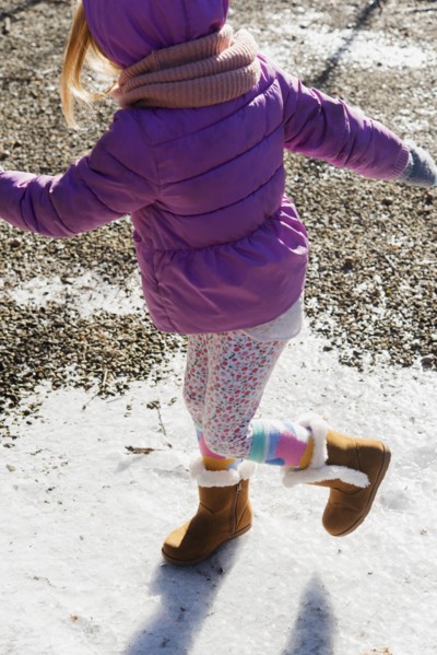 Girl wearing purple coat walking on snow