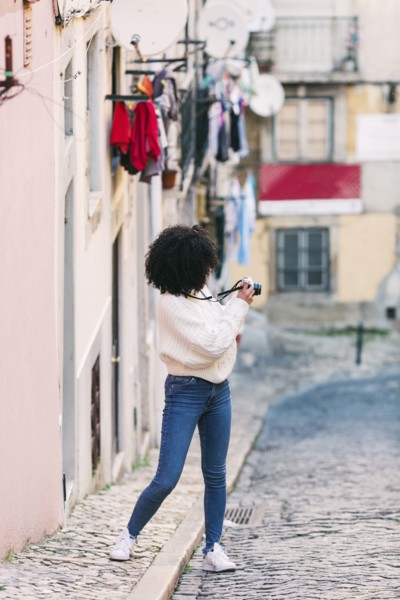 Young woman taking photograph in alley