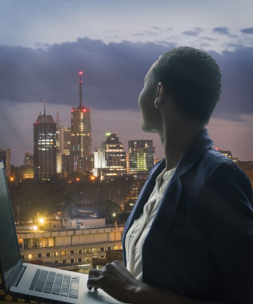 Businesswoman holding laptop by city skyline at sunset in Nairobi, Kenya