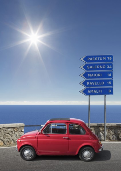 Red car by road sign on Amalfi Coast, Italy