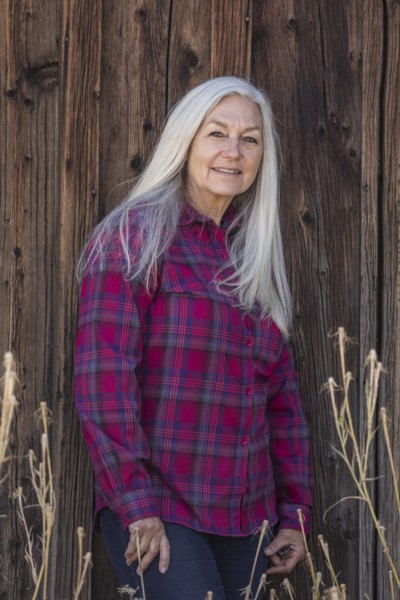 Mature woman wearing checked shirt by wooden wall