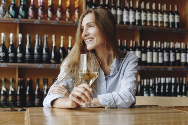 Smiling young woman holding glass of white wine