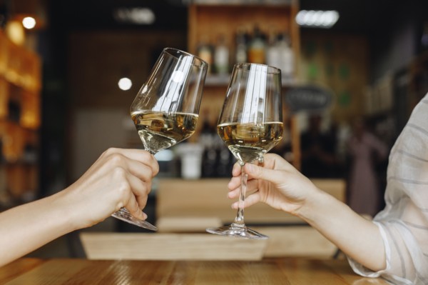 Hands of women toasting with glasses of white wine