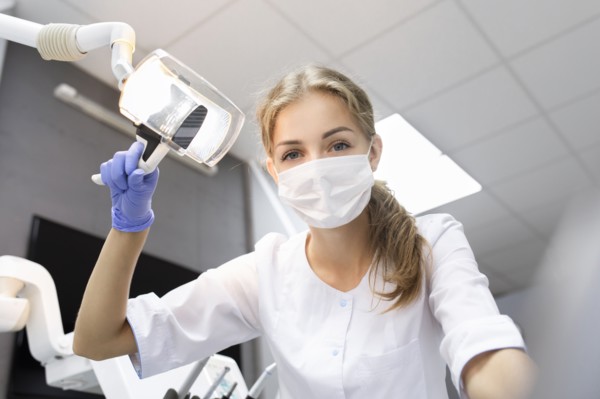 Patient point of view of dental assistant holding light