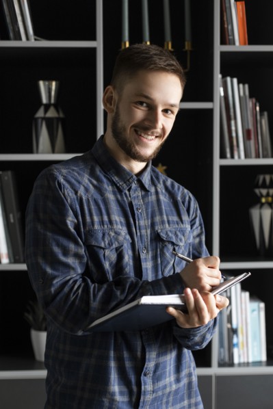 Smiling young businessman writing in note pad