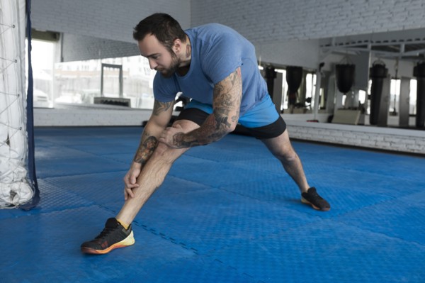 Mid adult man stretching in gym