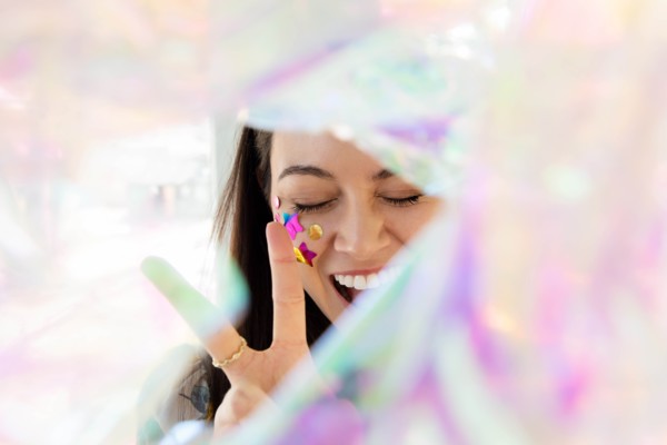 Woman with confetti on cheek making peace gesture
