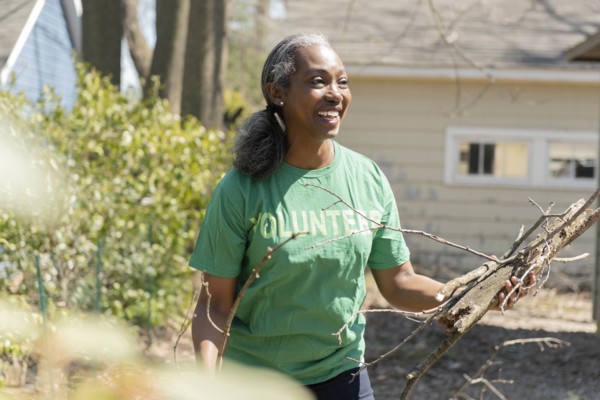 Mature woman volunteer collecting branches in garden