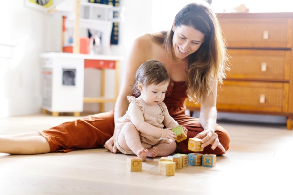Woman and her baby daughter playing with toy blocks
