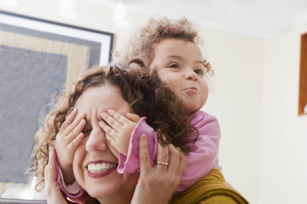 Girl with her hands covering her mother's eyes