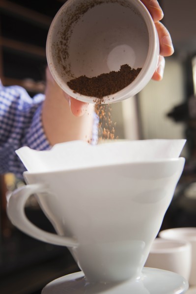 Barista pouring coffee grounds into filter
