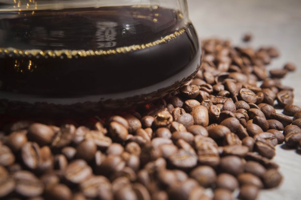 Jug of coffee on roasted coffee beans