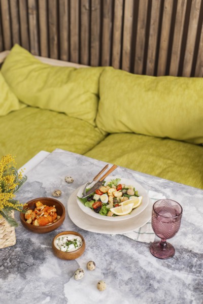 Caesar salad and sauce on table by sofa